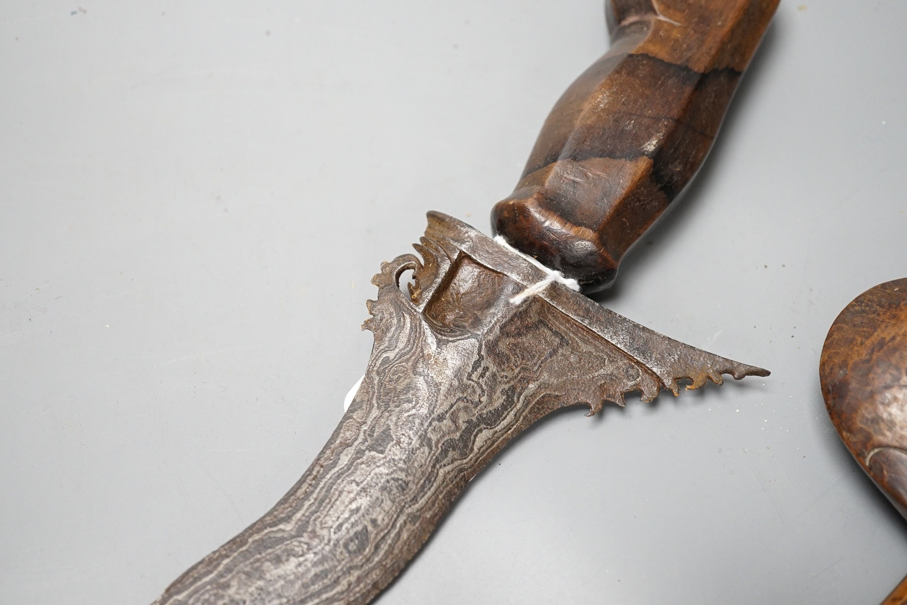 An Indonesian dagger kris, 19th century, earlier wavy black and silver-coloured watered blade, carved wooden handle and scabbard, blade 44.5cms